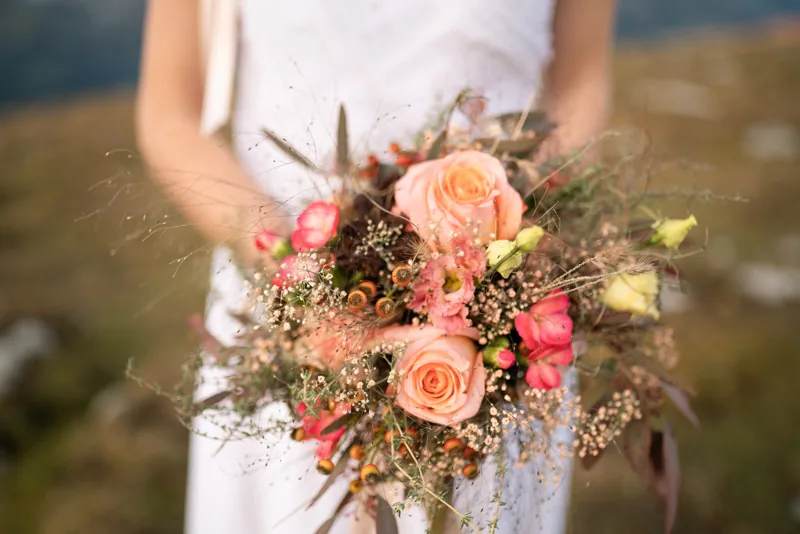 Braut hält ihren Strauss aus Rosen und Gräsern, Nahaufnahme