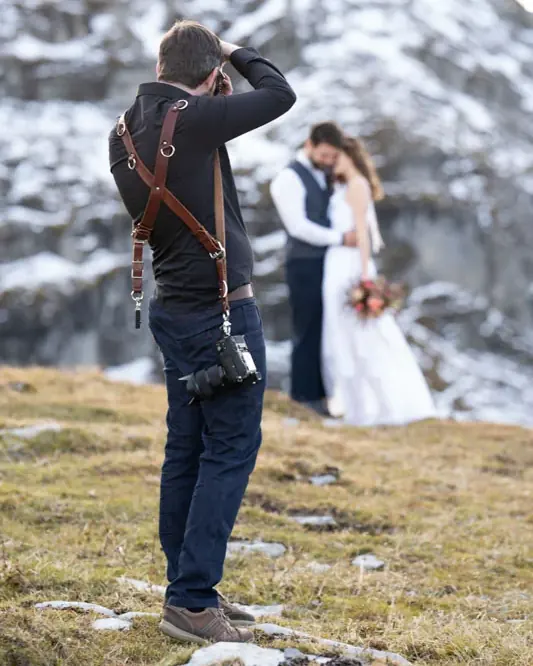 Reto Lieberherr fotografiert ein Brautpaar auf einer verschneiten Alp, die Kamera vor dem Gesicht