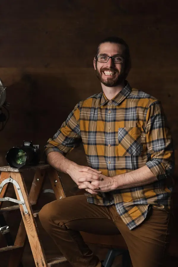 Reto Lieberherr, Hochzeitsfotograf aus Ebnat-Kappel im Toggenburg, sitzt lachend in seinem Atelier